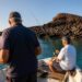 Twee vissers aan het vissen vanaf een boot met zicht op de rotsachtige kust van Lanzarote